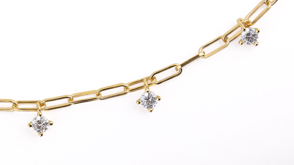 Collier NOXY en argent sterling 925, disponible en finition argentée ou dorée, orné de zircones blanches suspendues.